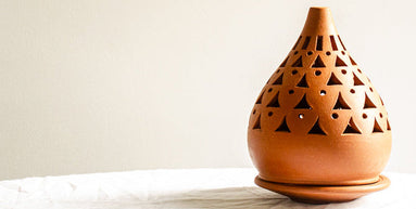 Terracotta oil burner with geometric design on a white surface
