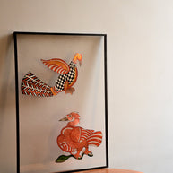 Tholu Bommalata puppets - Hamsa and checkered bird pair in vermilion, black and white, shown mounted for display on a round wooden table