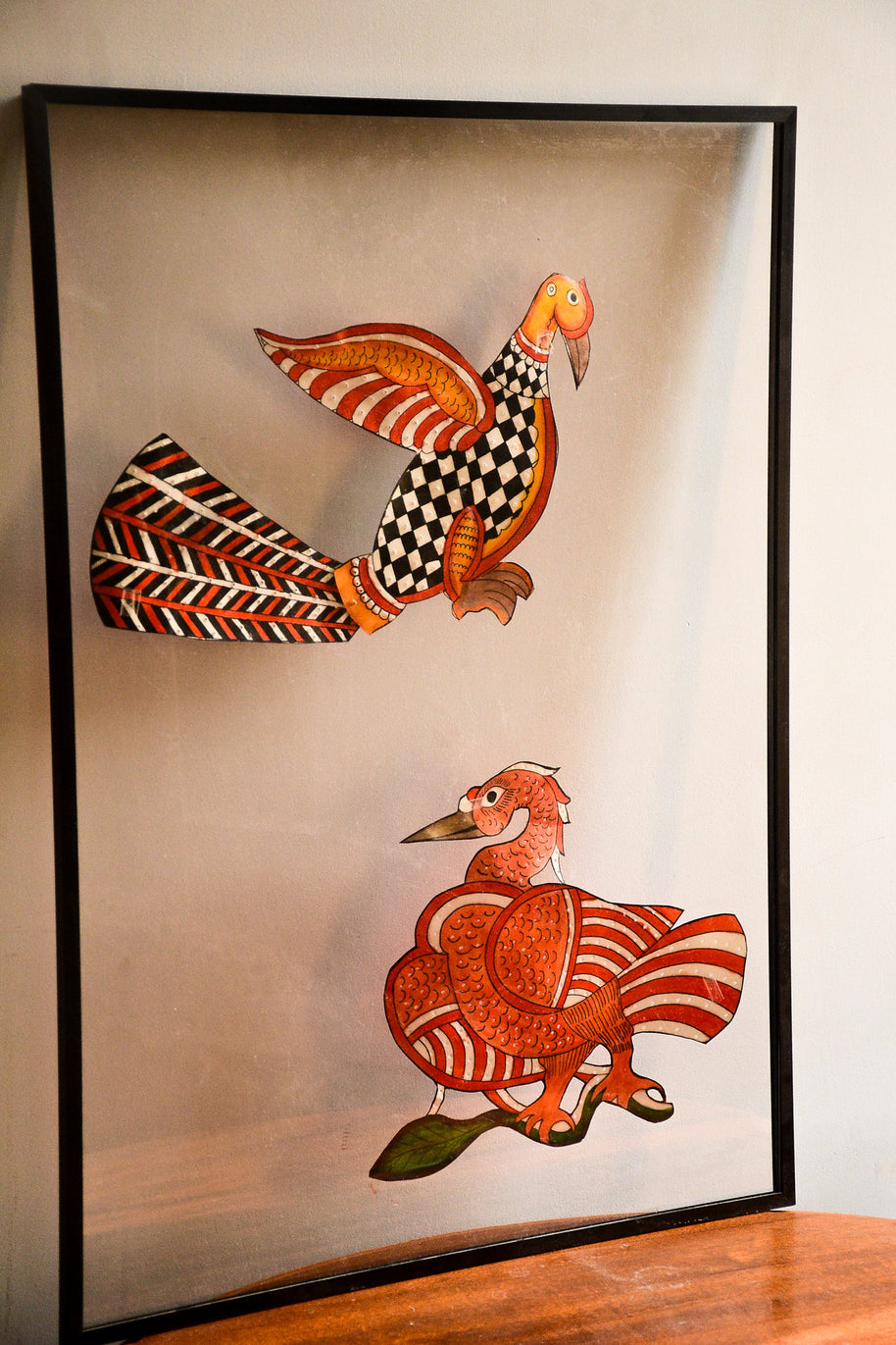 Close view of Tholu Bommalata leather puppets - checkered bird in flight and a Hamsa resting on a leafy branch, showing hand-pricked perforations