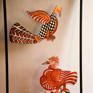 Close view of Tholu Bommalata leather puppets - checkered bird in flight and a Hamsa resting on a leafy branch, showing hand-pricked perforations
