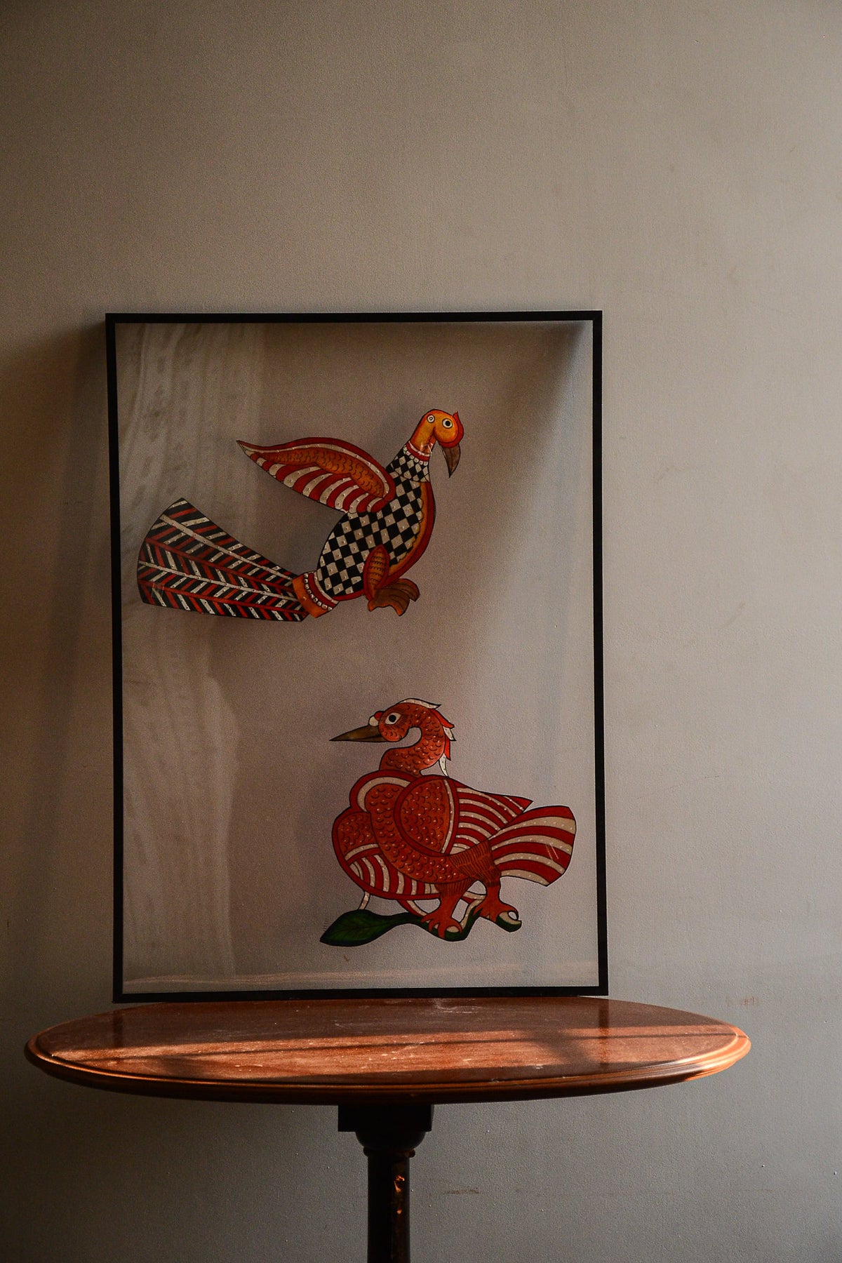 Tholu Bommalata leather puppets - checkered bird with fanned chevron tail above a Hamsa on a branch, shown mounted for display