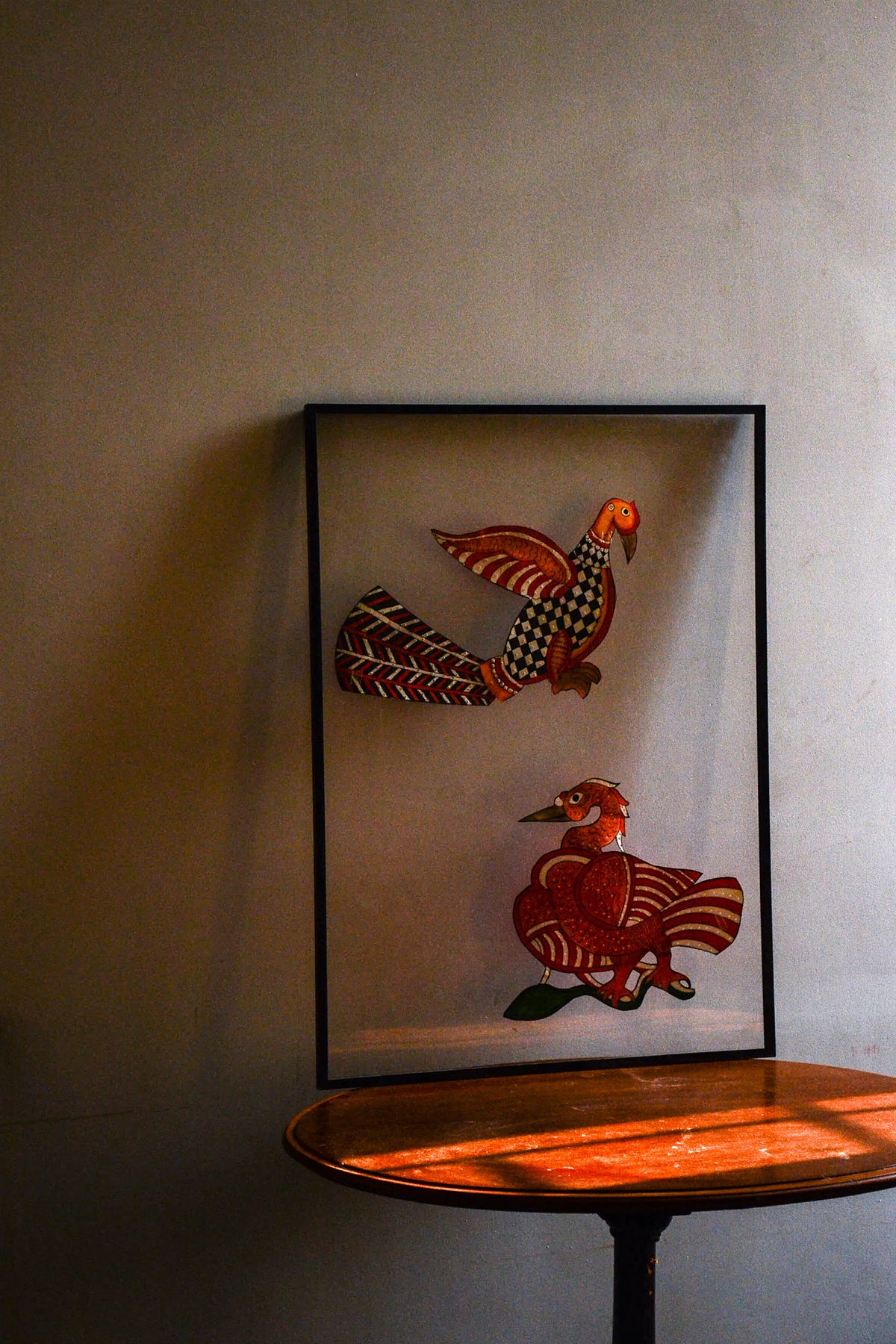 Tholu Bommalata puppets - Hamsa and checkered bird in warm evening light, shown mounted for display on a wooden table