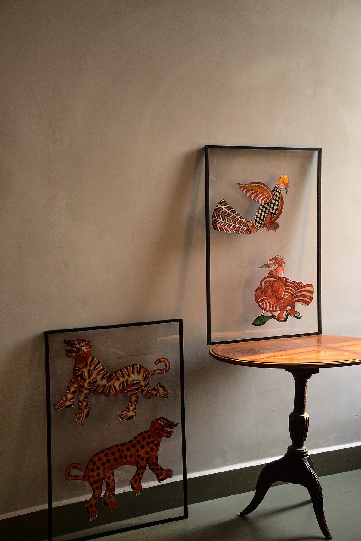 Tholu Bommalata leather puppet pairs - tiger and leopard leaning against the wall, Hamsa and checkered bird on a pedestal table