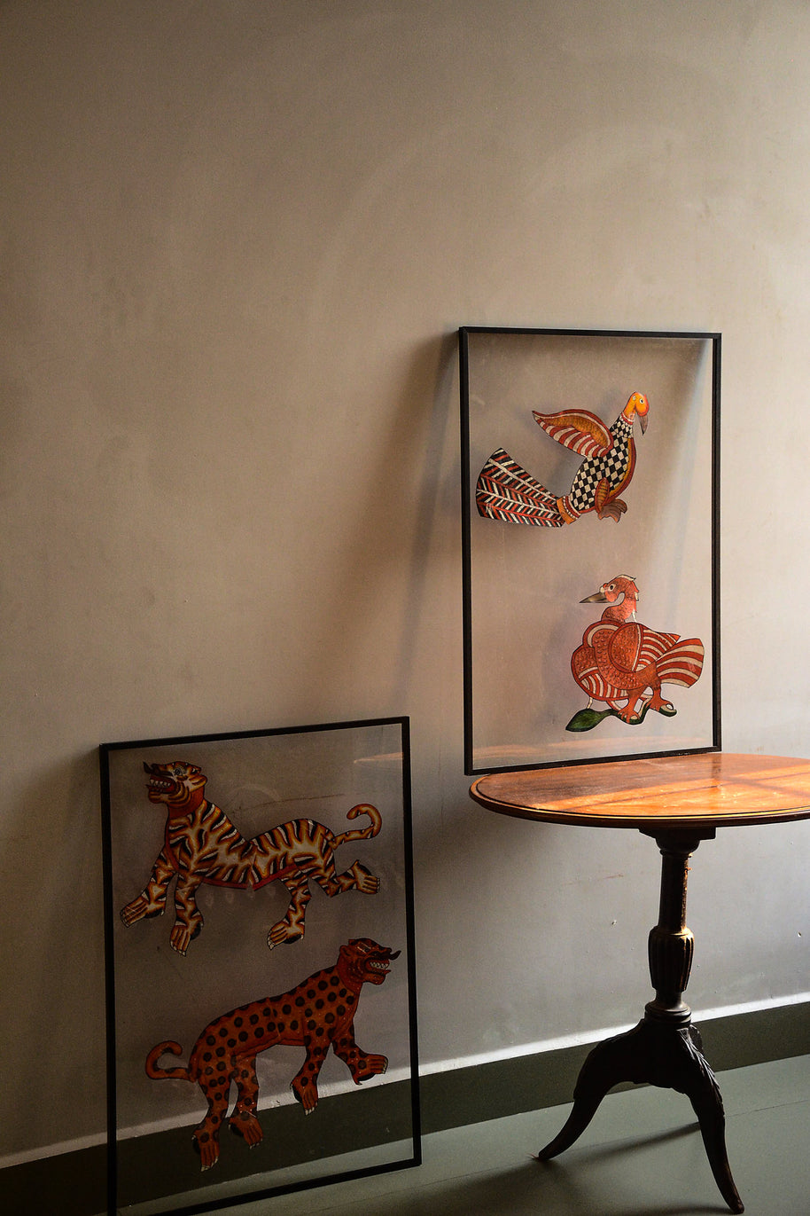 Tholu Bommalata leather puppet pairs - tiger and leopard leaning against the wall, Hamsa and checkered bird on a pedestal table