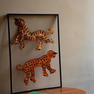 Tholu Bommalata leather puppets - tiger and leopard pair, hand-cut and hand-painted, shown mounted for display above a wooden pedestal table
